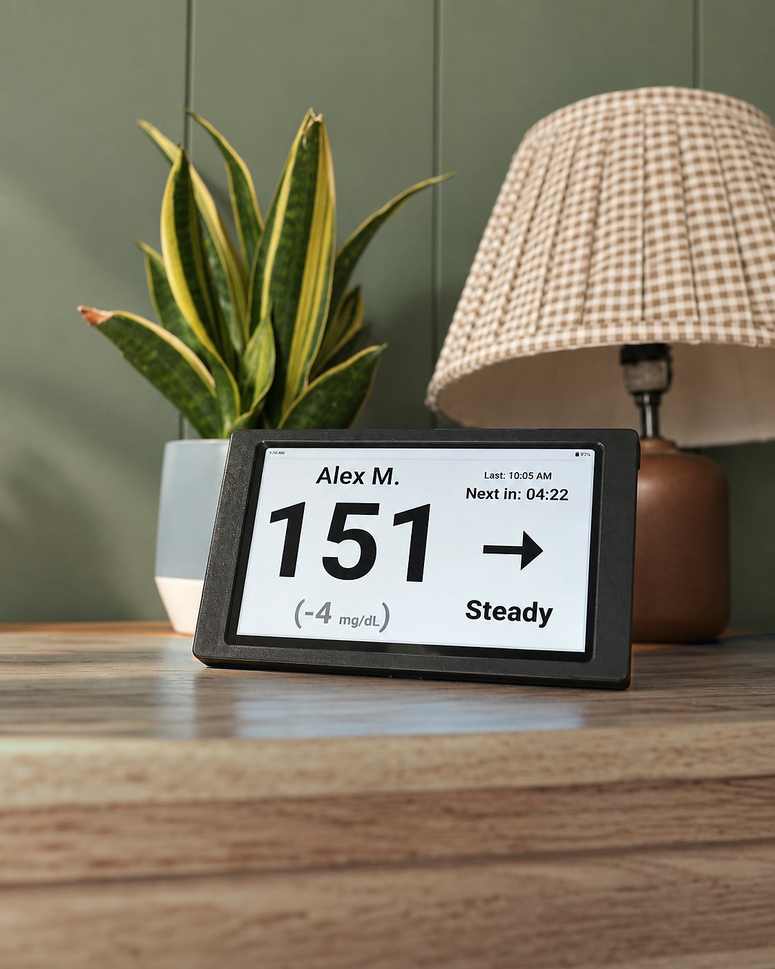 Black Glucose Display on a wooden table in a softly lit room, showing the light dashboard.
